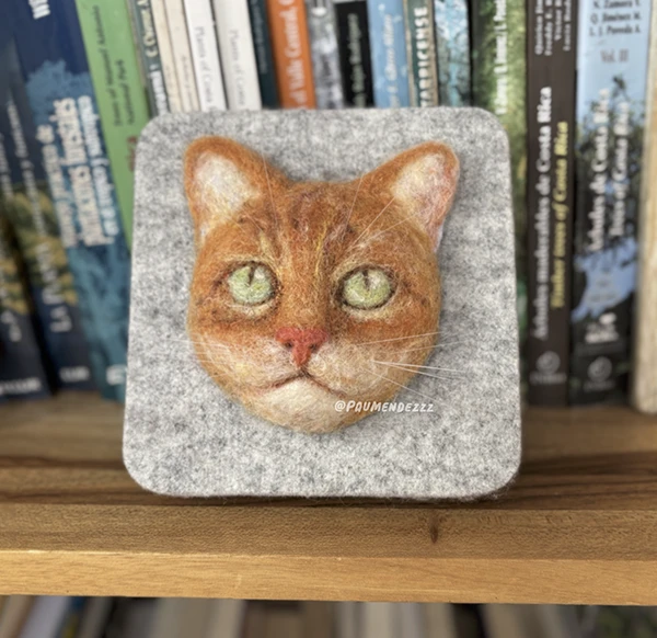 Retrato en fieltro de un gato naranja sobre una placa de lana gris