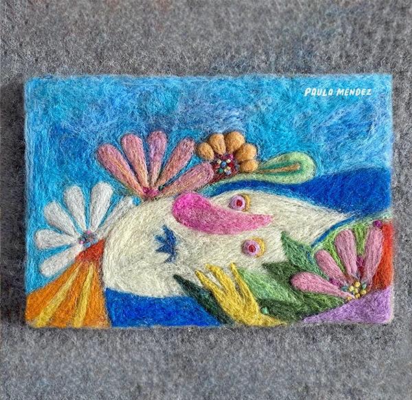 Cuadro en fieltro con una criatura entre flores y fondo azul